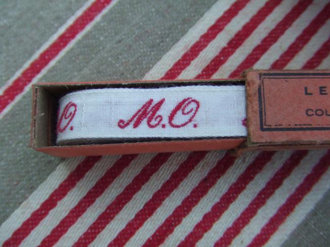 Boite de ruban blanc avec initiales 'MO' tissées en rouge 1920,